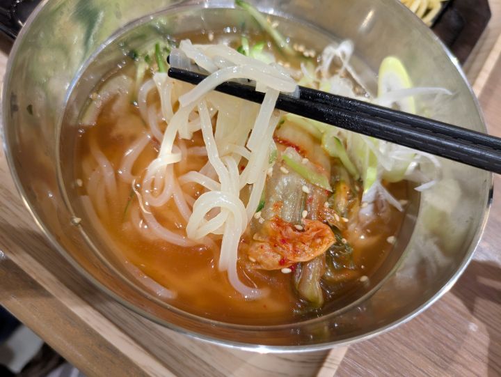 箸でコシのある麺を持ち上げている、牛角焼肉食堂の冷麺