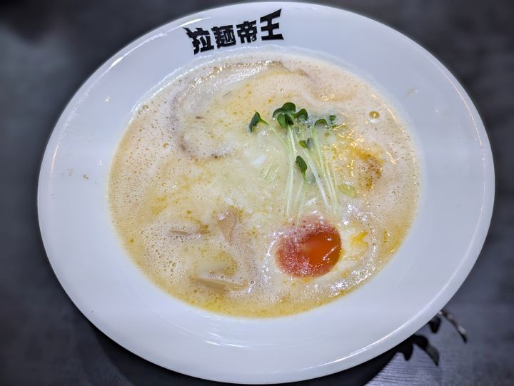 少し表面が泡立ったクリーミーな白湯スープに玉ねぎやスプラウトが乗った拉麺帝王の鶏そば