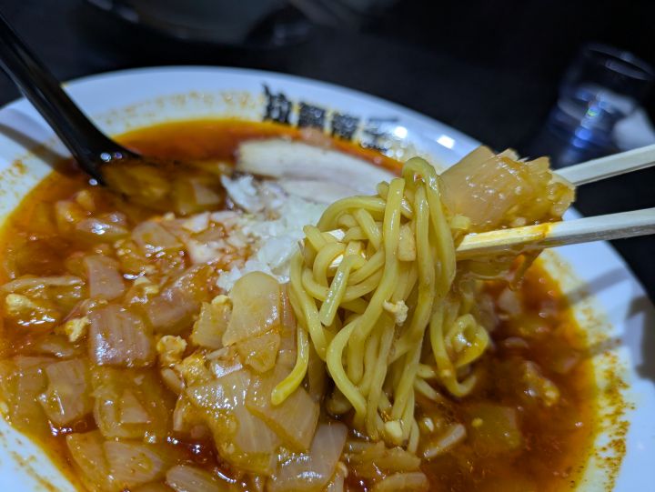 真っ赤なスープがよく絡む拉麺帝王の中太麺を箸で持ち上げた様子