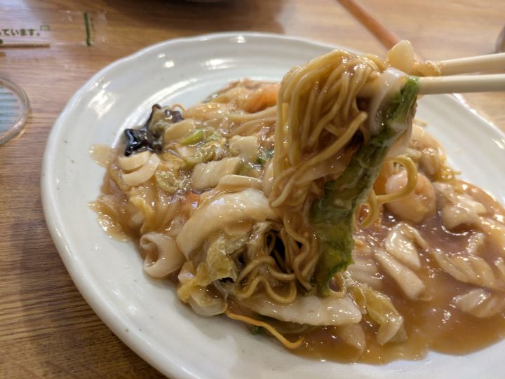 モンシェリーの中華風やきそばの香ばしい細麺をとろみのある餡ごと箸で持ち上げている様子