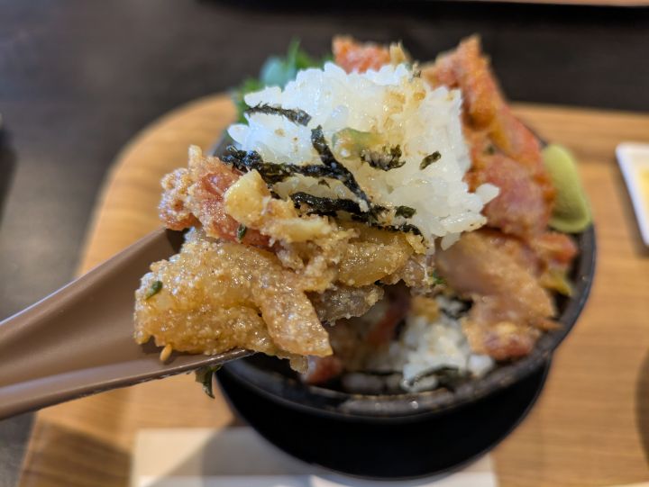 濃厚なゴマダレが絡んだ「KUTTAまかない丼」の色々な海鮮をスプーンで持ち上げている様子