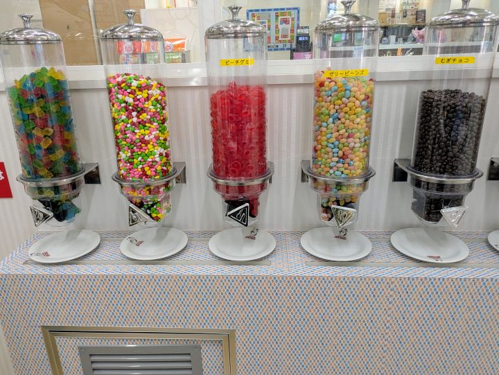 透明なケースにぎっしり詰まった色鮮やかなグミ、チョコレートなどの各種お菓子