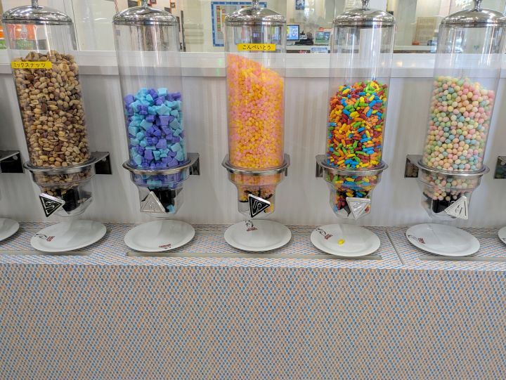 透明なケースにぎっしり詰まった色鮮やかなグミ、ミックスナッツ、こんぺいとうなどの各種お菓子