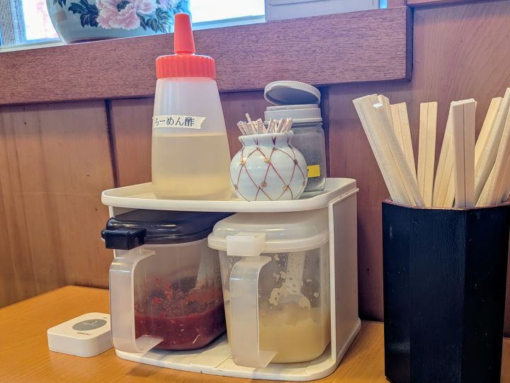 テーブルに置かれたらーめん酢、にんにく、豆板醤などの卓上調味料。