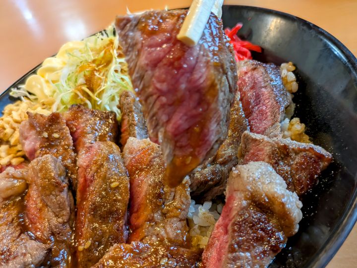 箸で持ち上げた柔らかそうな牛赤身肉ステーキ。