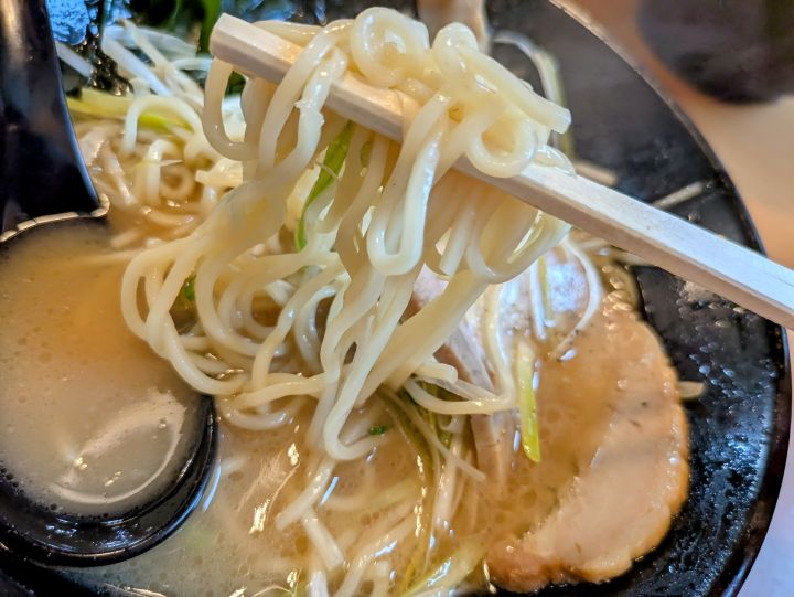 箸で持ち上げたネギラーメンの自家製細麺。
