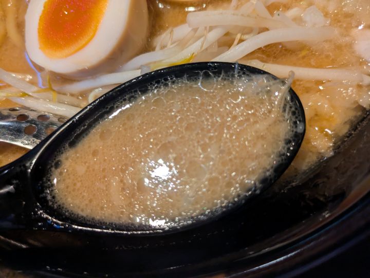 レンゲですくった濃厚な豚骨醤油スープ