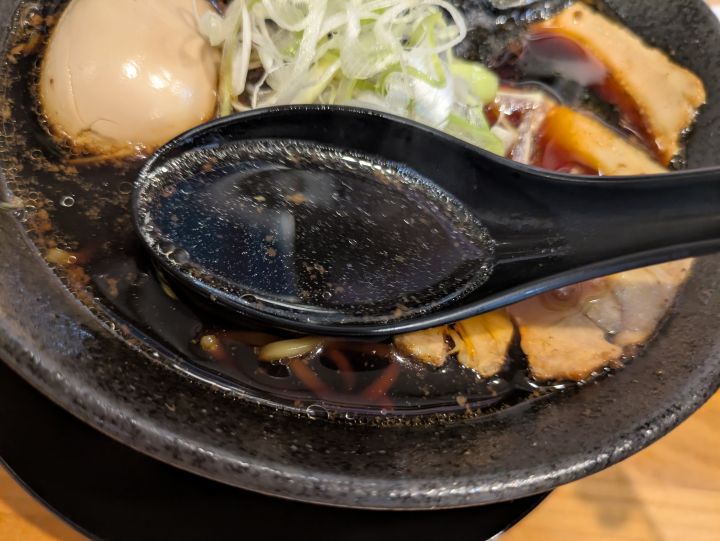 木更津ラーメン大輝のブラックラーメンの黒いスープをレンゲですくった様子