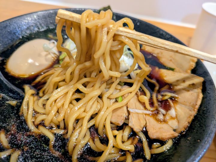 木更津ラーメン大輝のブラックラーメンの麺を箸で持ち上げた様子