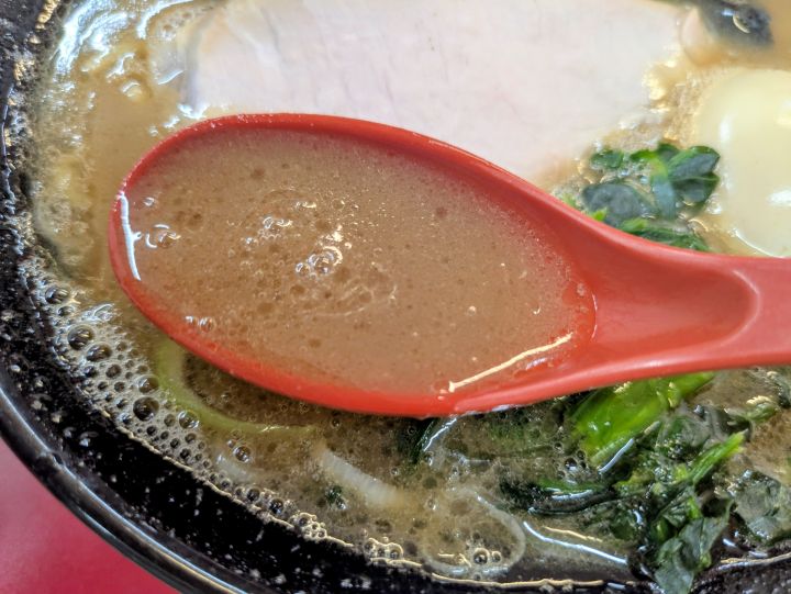 かわみ家のとろみのある家系スープをレンゲですくったアップ